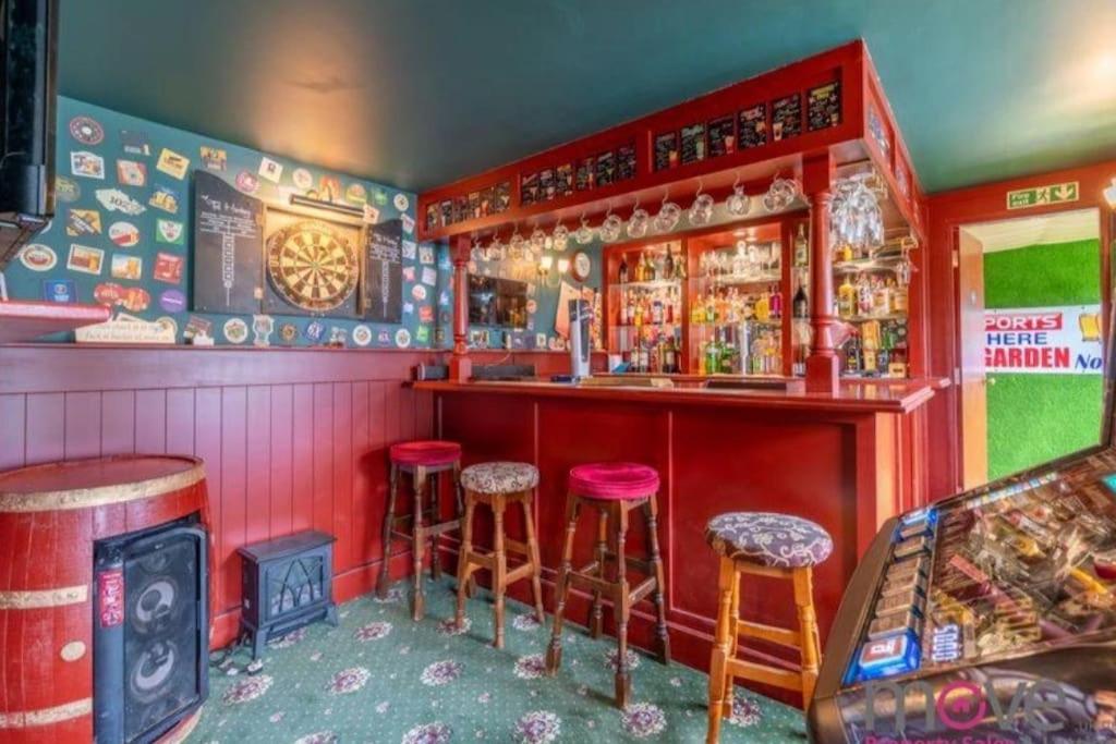 a bar with four stools in a room with aperature at Modern 4 bed home, hottub and traditional pub in Down Hatherley