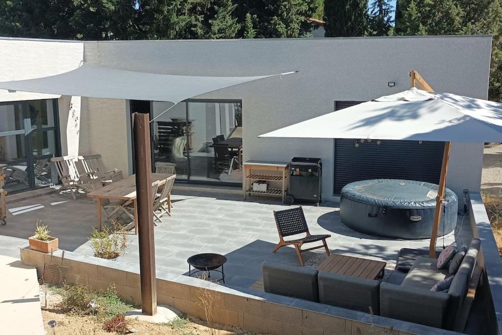 une terrasse avec un canapé, un parasol et une table dans l'établissement Magnifique villa avec jacuzzi et billard, à Limoux