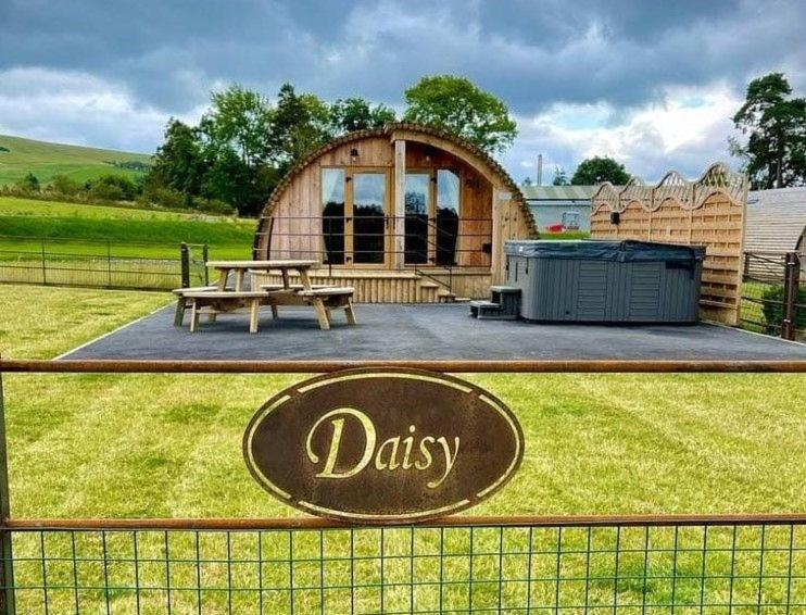 a wooden cabin with a picnic table and a sign on a fence at Daisy in Rhayader