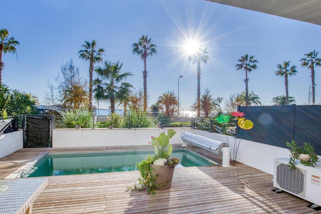 ein Pool mit Palmen im Hintergrund in der Unterkunft La Palmeraie - Appt climatisé - Piscine in Bandol