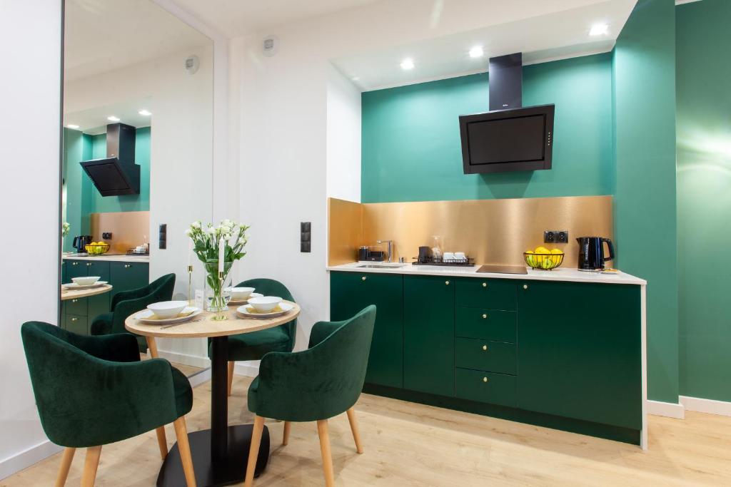 a kitchen with green cabinets and a table with chairs at SQUARE APARTMENTS GDYNIA in Gdynia