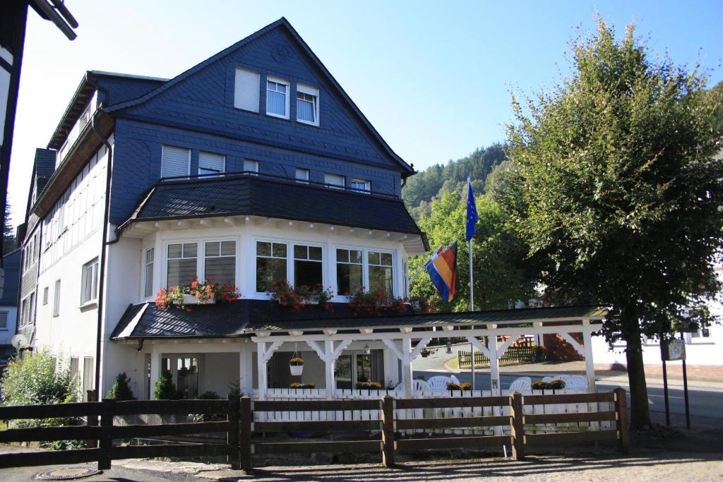 ein blau-weißes Haus mit einem Zaun davor in der Unterkunft Gasthof-Pension Hunaustuben in Schmallenberg