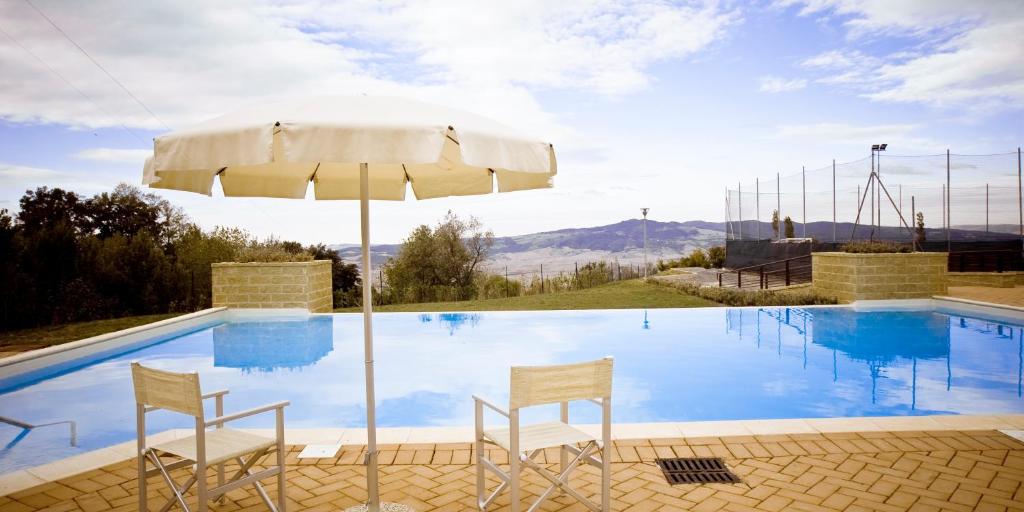 a swimming pool with two chairs and an umbrella at Bed & Bike in Volterra