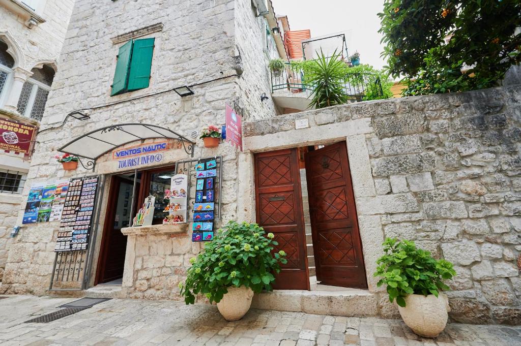 a stone building with two doors and two potted plants at Apartments Ivica in Trogir