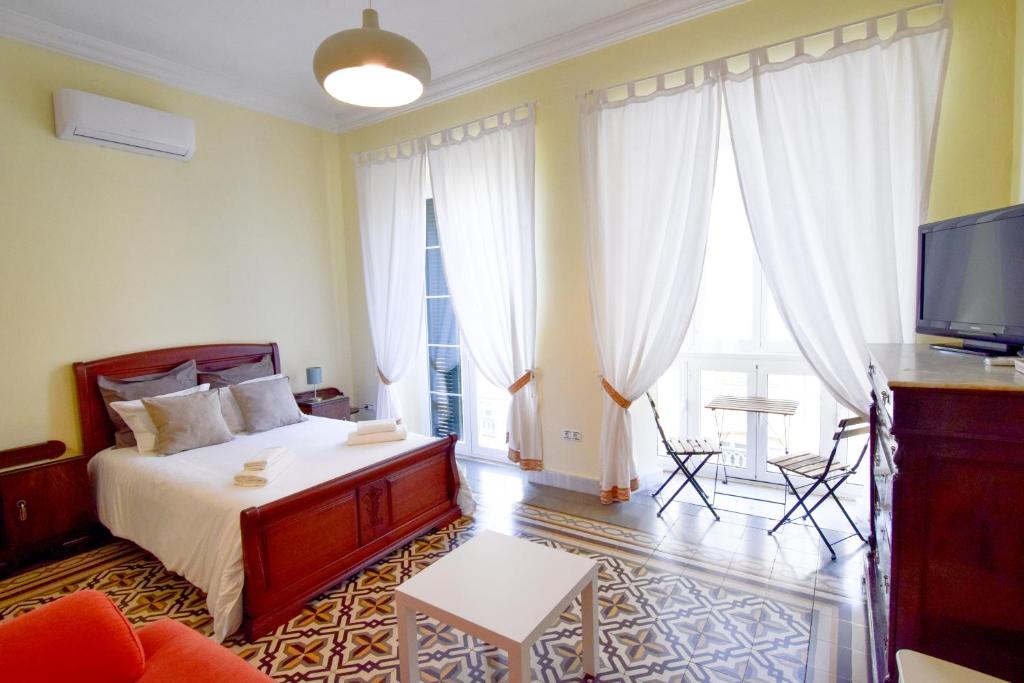 een slaapkamer met een bed en een tv en een bank bij Letmalaga Soho Apartment in Málaga