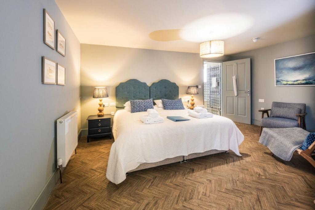 a bedroom with a large white bed and a chair at The Globe Inn in Wells next the Sea