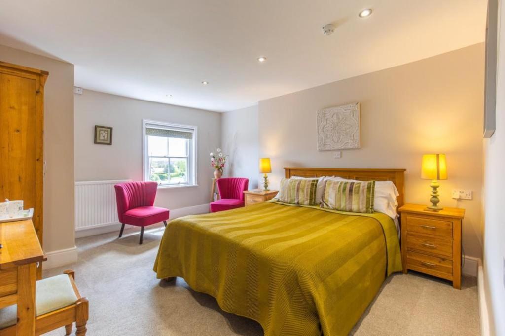 a bedroom with a bed and two pink chairs at The Globe Inn in Wells next the Sea