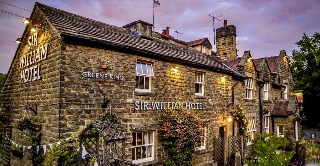 a stone building with a sign on the side of it at Sir William Hotel in Grindleford Bridge