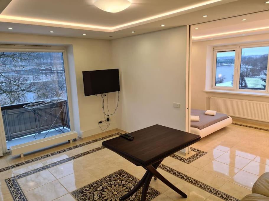 uma sala de estar com uma mesa e uma televisão na parede em River view appartment in Kaunas em Kaunas