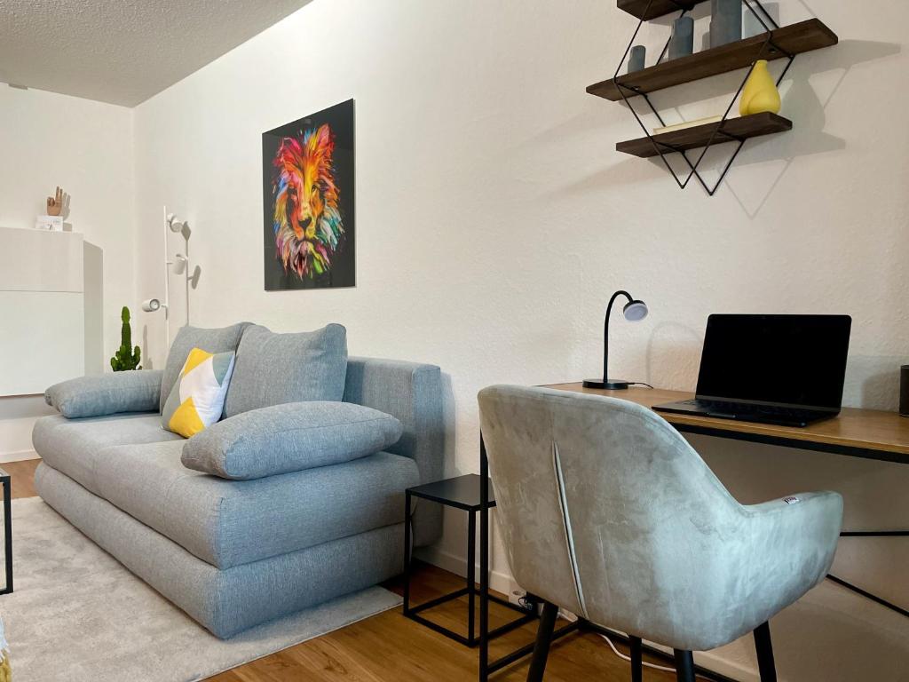 a living room with a couch and a desk with a laptop at Modernes Apartment I Parkplatz I Netflix I Zentrum in Renningen