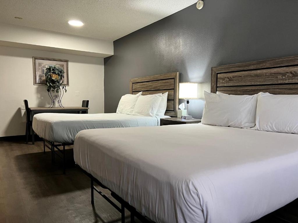 two beds in a hotel room with white sheets and pillows at Siegel Slots and Suites (No Resort Fees) in Las Vegas