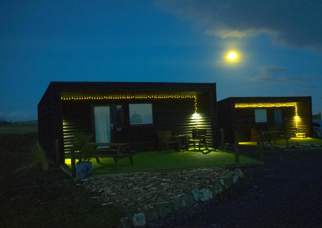 a house with lights on the side of it at night at The Windy Roost in Occumster