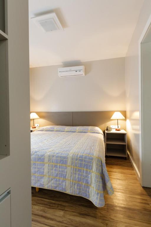 a bedroom with a bed with a blue and white blanket at Apart Hotel Garibaldi in Porto Alegre