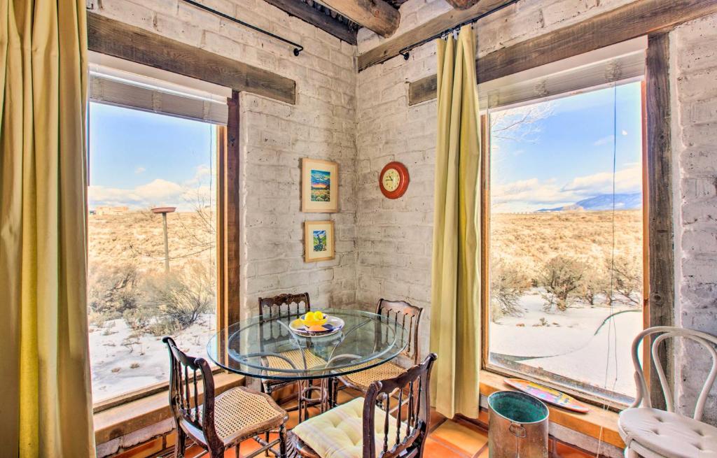uma sala de jantar com uma mesa de vidro e uma grande janela em Casita Vacation Rental Near Taos with Patio! em El Prado