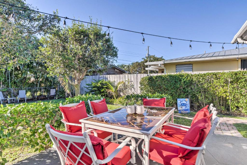 a patio with red chairs and a glass table at Bright Boynton Beach Getaway with Patio! in Boynton Beach