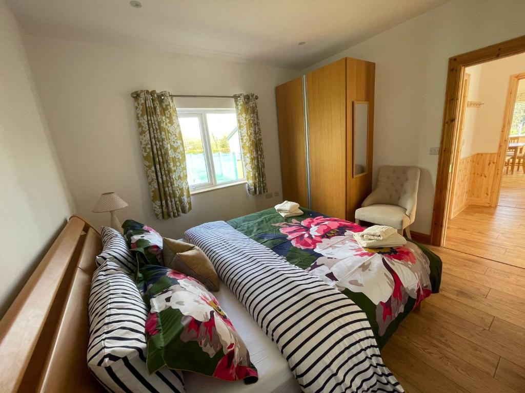 a bedroom with two beds and a chair and a window at Pine Lodge in Lisnaskea