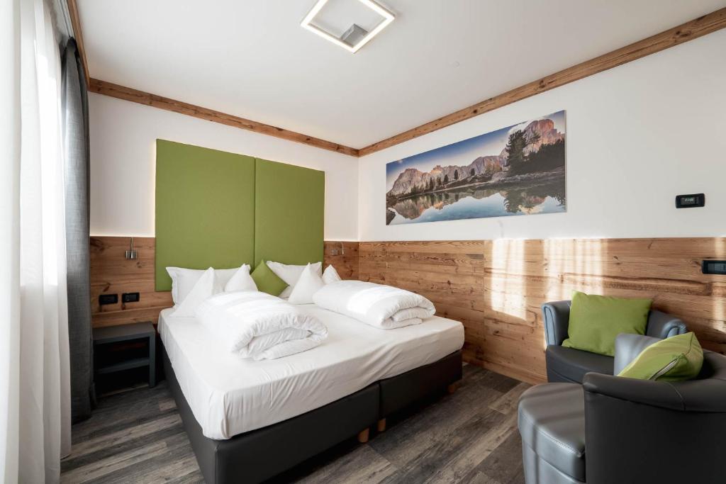 a hotel room with a bed and two chairs at Hotel Chalet Sas Morin in Pozza di Fassa