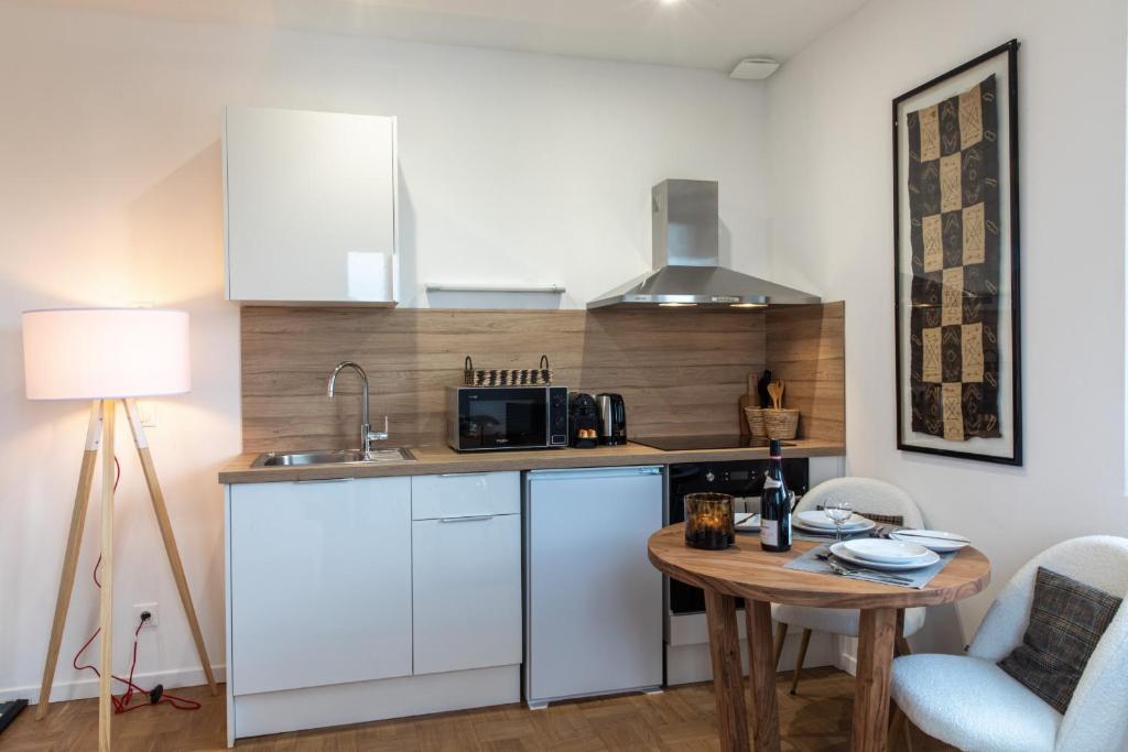 a kitchen with white cabinets and a table in a room at DIFY Chalet a la ville - Parilly in Vénissieux