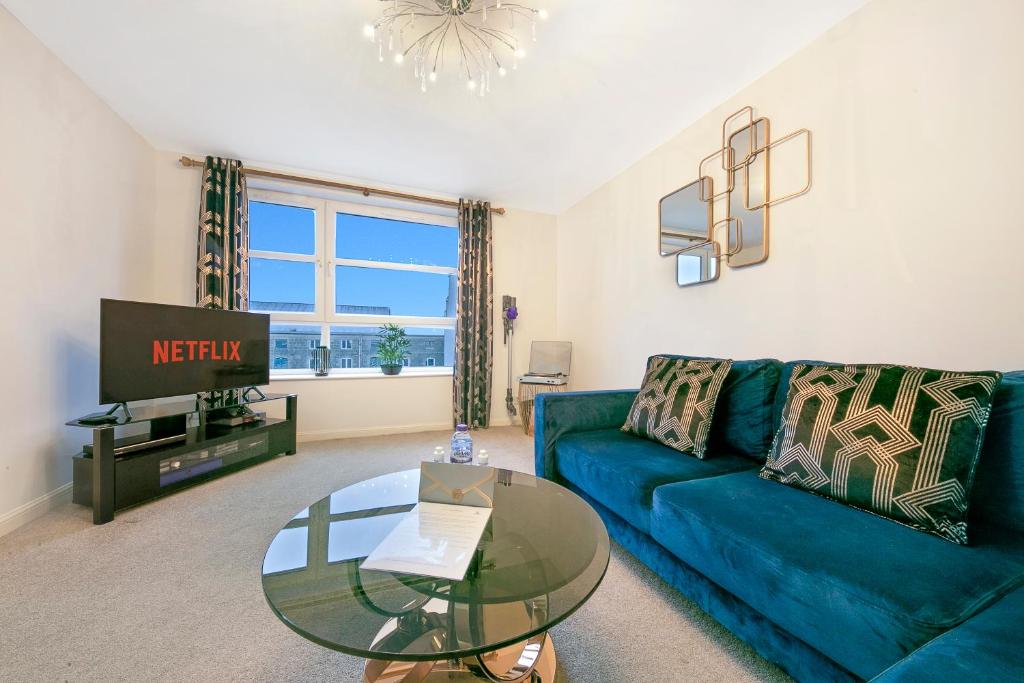 a living room with a blue couch and a glass table at Kings Lodge - Grampian Lettings Ltd in Aberdeen