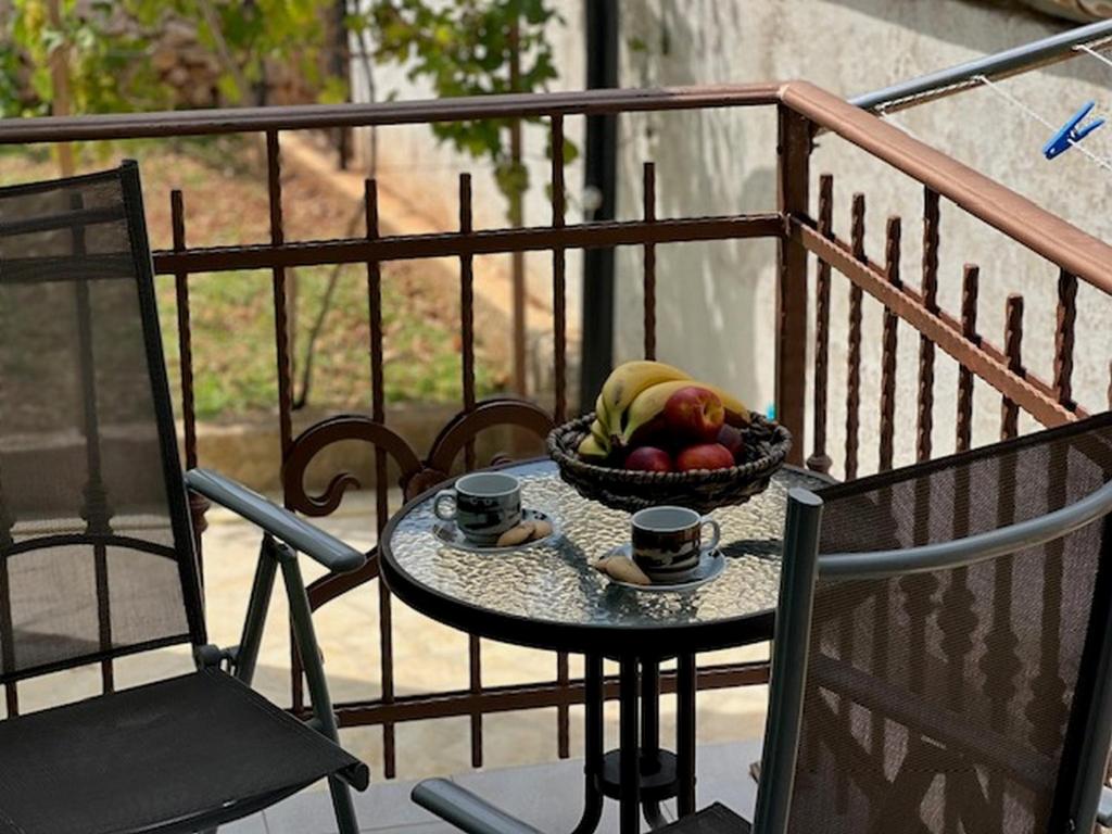 uma mesa com uma tigela de fruta e duas chávenas numa varanda em Holiday Home Lupita 2 em Vinjerac