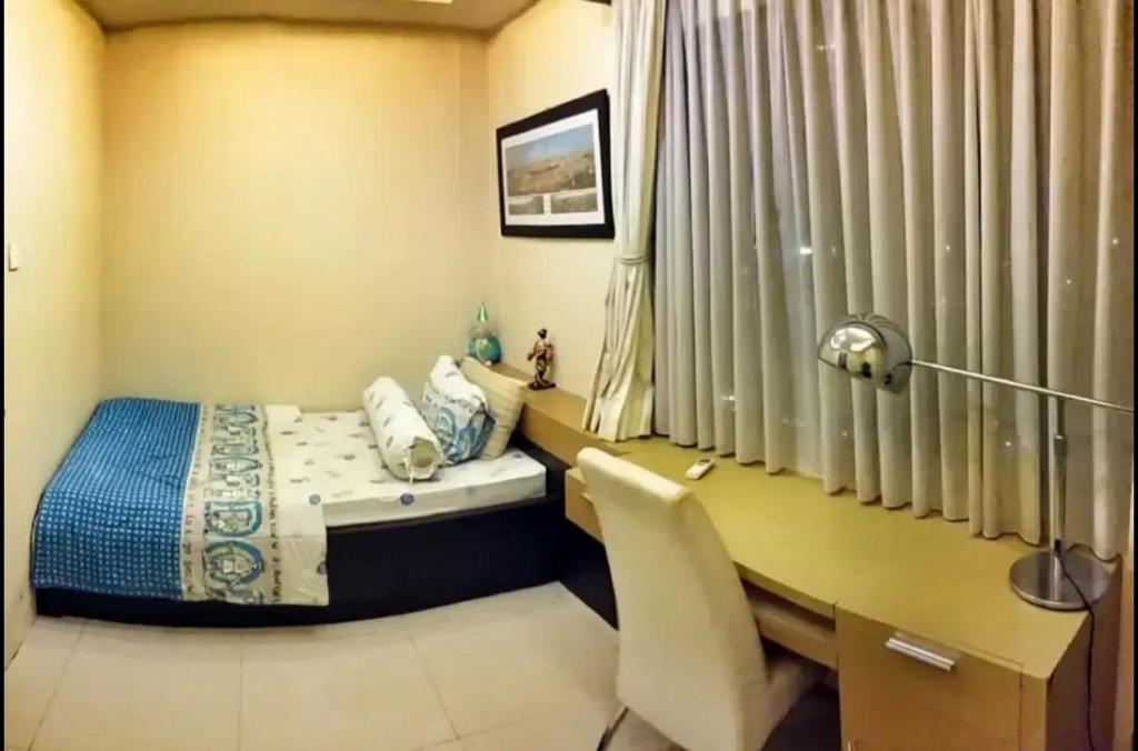 ein kleines Schlafzimmer mit einem Schreibtisch, einem Bett und einem Schreibtisch in der Unterkunft Cosmo mansion apartment in Jakarta