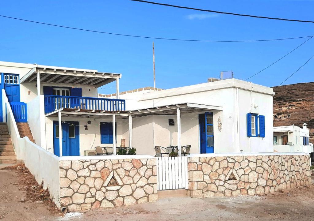 een wit huis met blauwe ramen en een stenen muur bij Seaside Residence Kiki Prassa,Kimolos in Kimolos