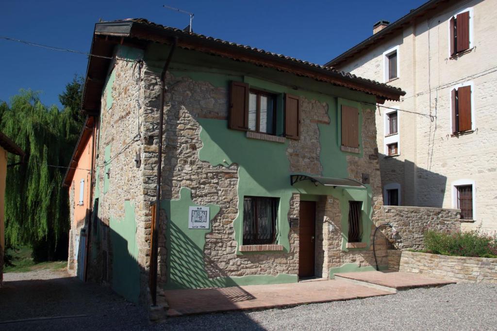 una vecchia casa in pietra con vernice verde a lato di La Ca' Tòrta - Casa intera a Neviano degli Arduini