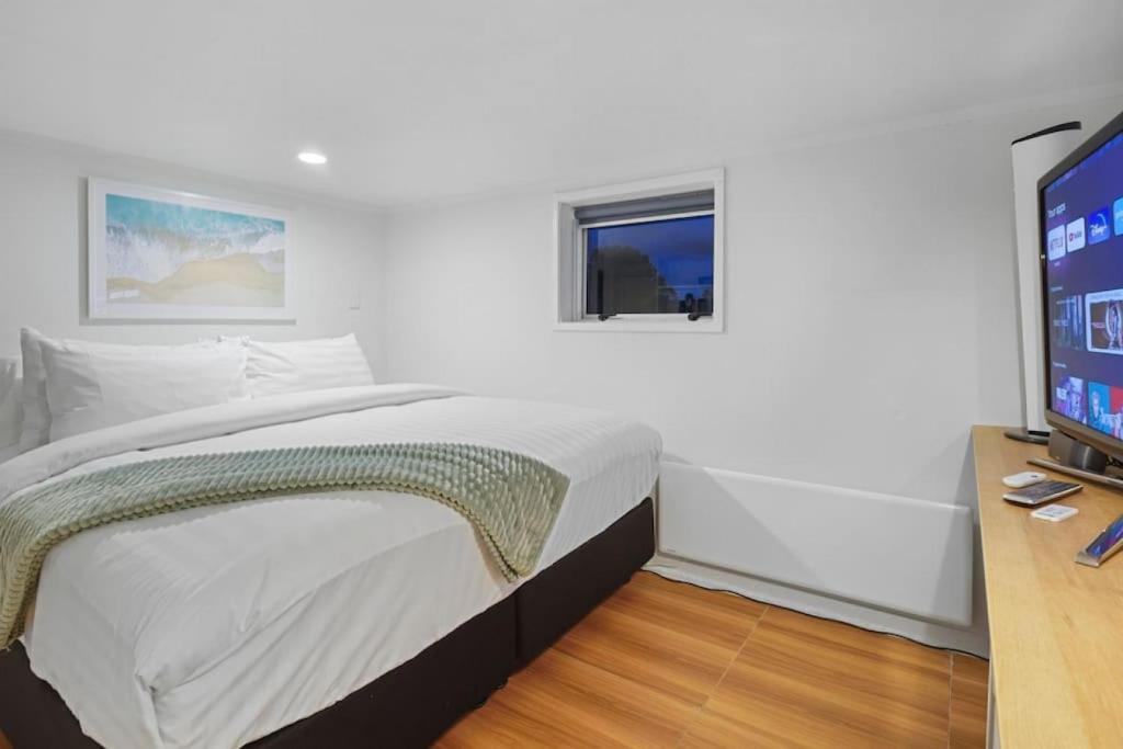 een slaapkamer met een bed en een flatscreen-tv bij Newly Renovated Studio w Parking - Wifi - Netflix in Auckland