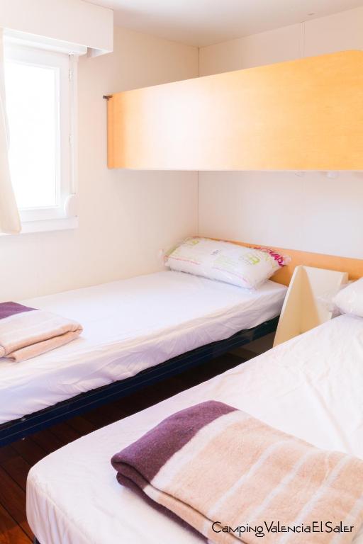 a room with two beds and a window at Camping Valencia el Saler in El Saler