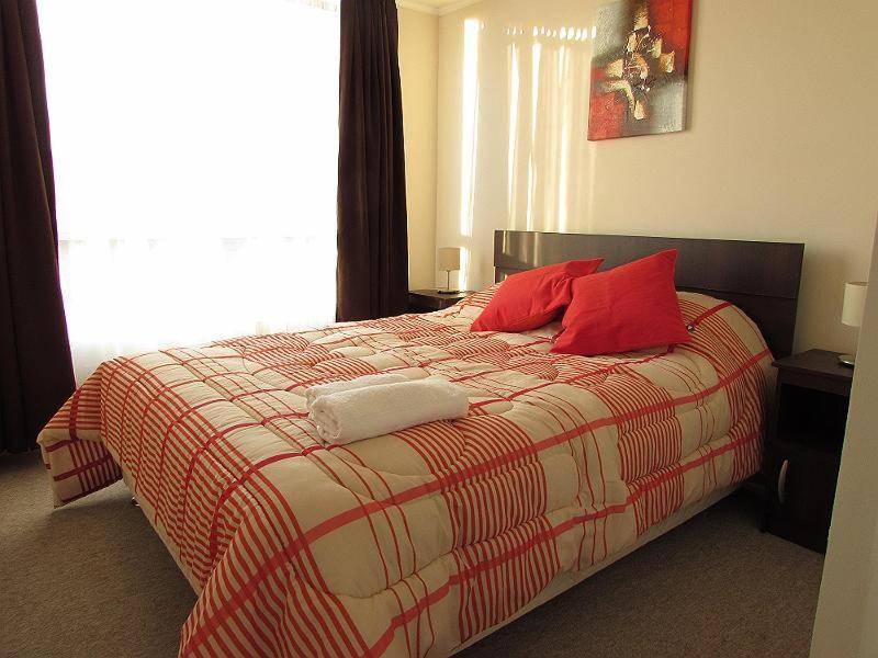 Un dormitorio con una cama con almohadas rojas y una ventana en Santiago Central Suites, en Santiago