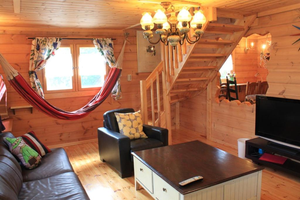 ein Wohnzimmer mit Couch und Fernseher in einer Blockhütte in der Unterkunft Farm Log Cottage Blueberry Annabel - Vacation STAY 36333v in Ito