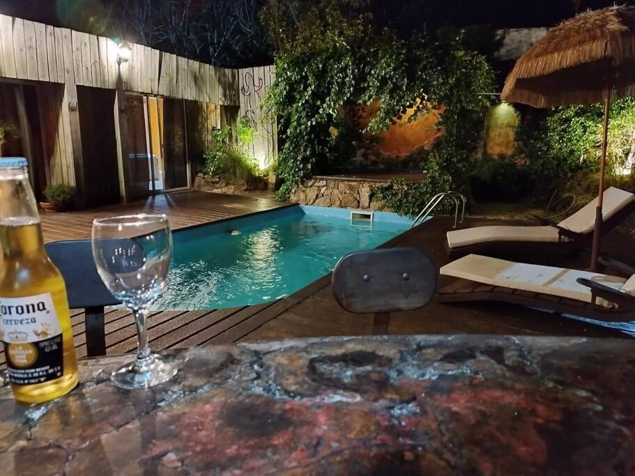 una botella de vino y una copa en una mesa junto a la piscina en La casa ideal para el momento que buscabas., en Punta del Este