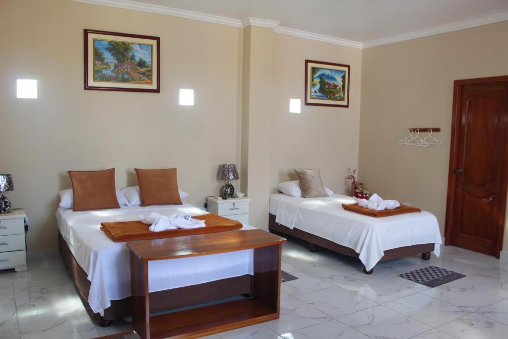 um quarto com 2 camas, uma secretária e uma mesa em Hostal Romy em Puerto Baquerizo Moreno