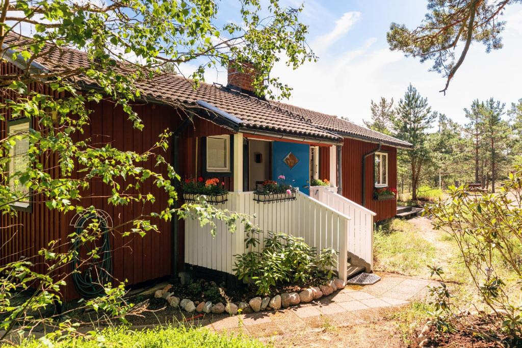 uma casa vermelha com uma cerca branca à frente. em Authentic Swedish family home on the archipelago em Stavsnäs