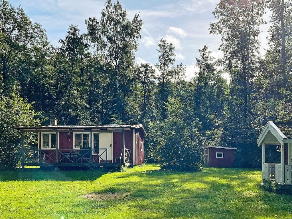 una pequeña cabaña roja en un campo con árboles en 5 person holiday home in LERDALA, en Lerdala