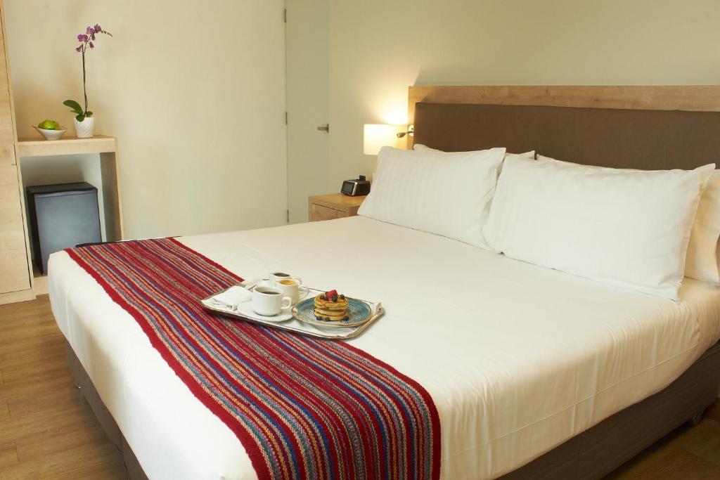 a hotel room with a bed with a tray of food on it at Hotel Estelar San Isidro in Lima
