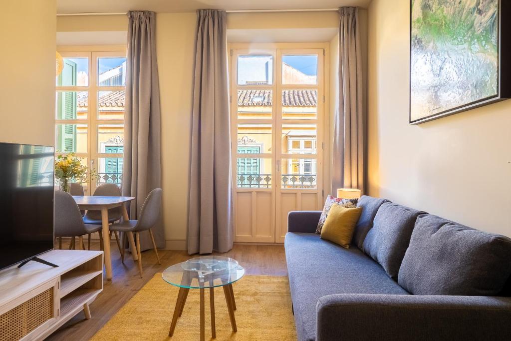 salon z niebieską kanapą i stołem w obiekcie Elegante 3 dormitorios en Centro Historico Málaga w Maladze