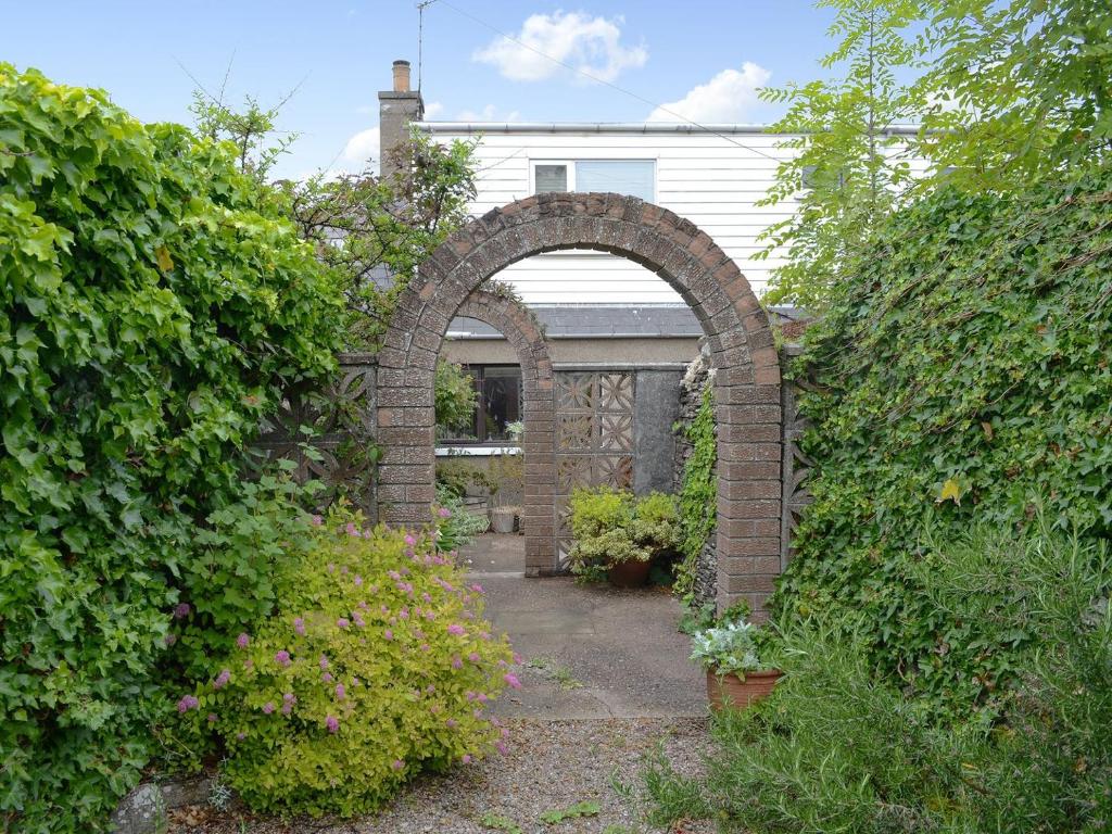 an archway in front of a house with bushes at Keith House in Thurso