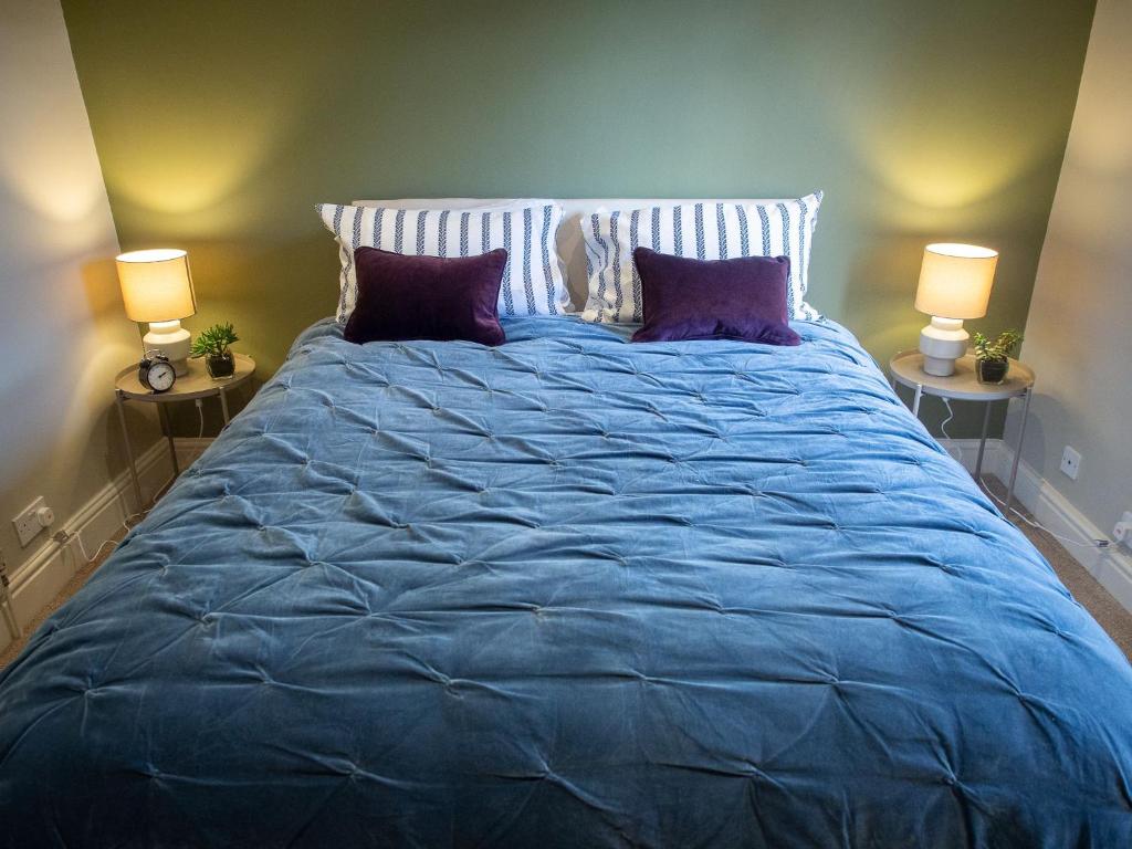 a large blue bed with purple pillows and two lamps at The Beeches - Chatsworth Apartment No 3 - Sleeps 2 in Baslow