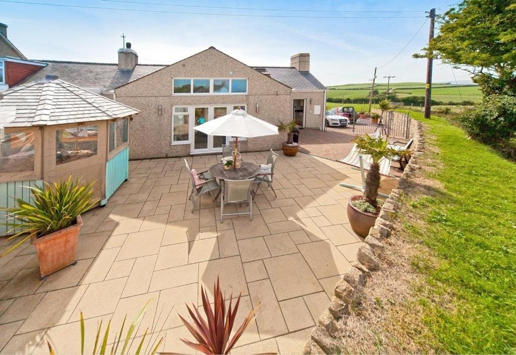 eine Terrasse mit Sonnenschirm und Tisch und Stühlen in der Unterkunft Pen Y Sarn in Abersoch