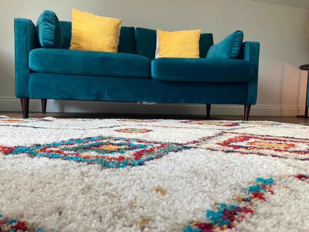 a blue couch in a living room with a rug at Lime Tree Cottage in Tillingham