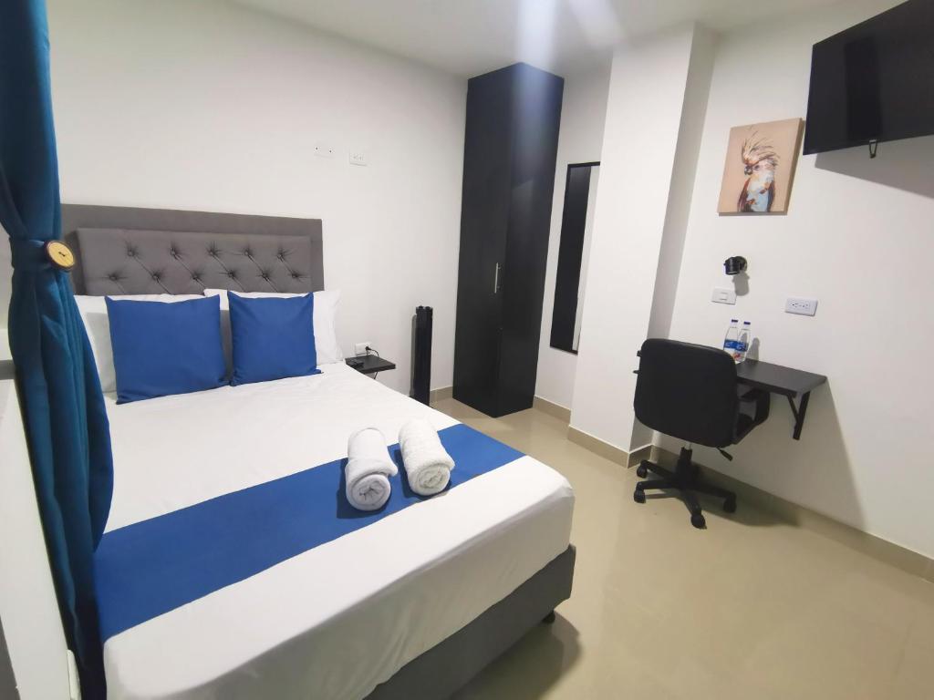 Schlafzimmer mit einem Bett mit blauen Kissen und einem Schreibtisch in der Unterkunft Andaliving Campo Valdes Hospedaje in Medellín