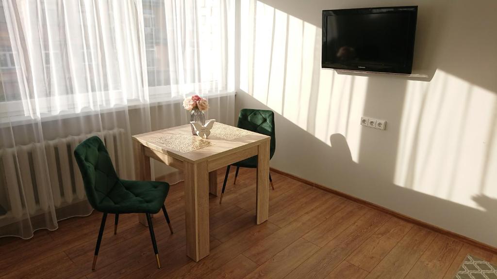 a small table with a vase of flowers and a television at Stay in center #Šiauliai in Šiauliai