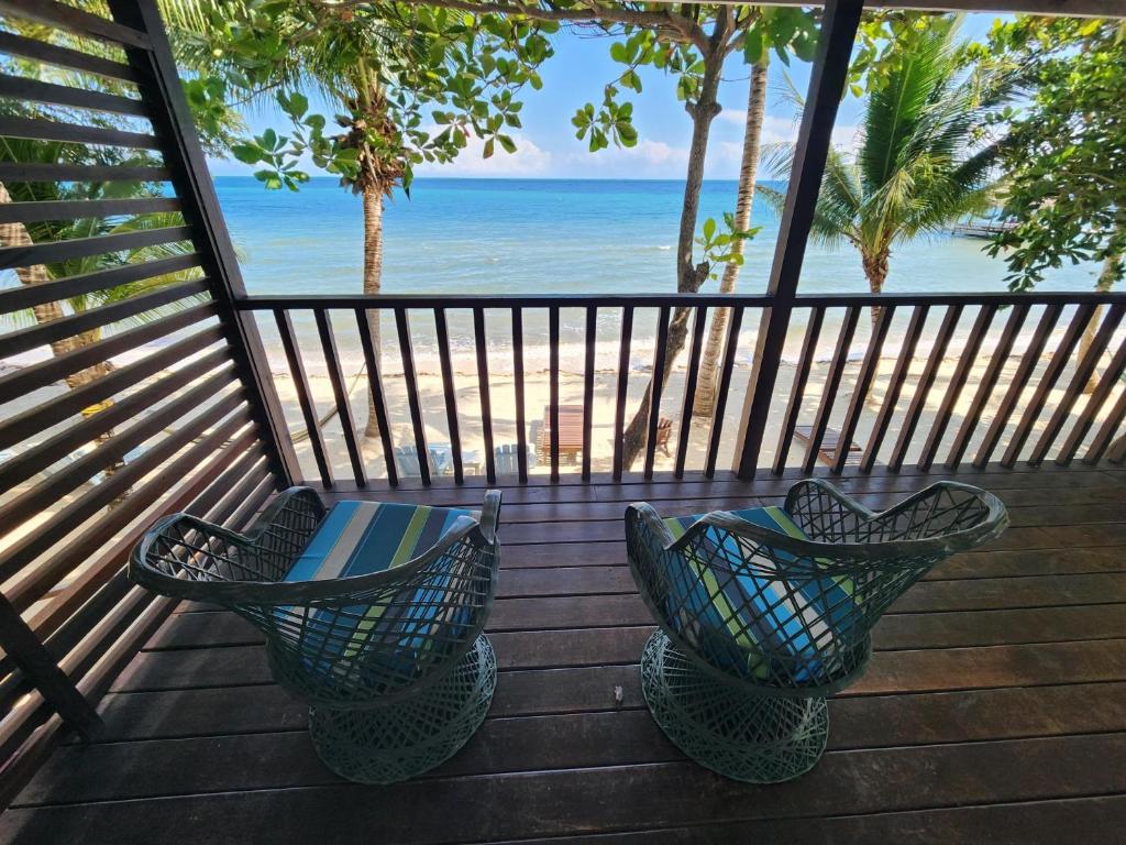 a balcony with two chairs and the ocean at Maya Beach Hotel in Maya Beach