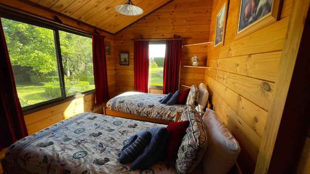 a bedroom with two beds in a log cabin at Fantail Garden in Walton