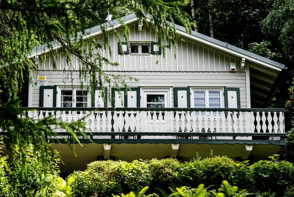 a white house with a porch and trees at Willa Tyrolczyk in Karpacz