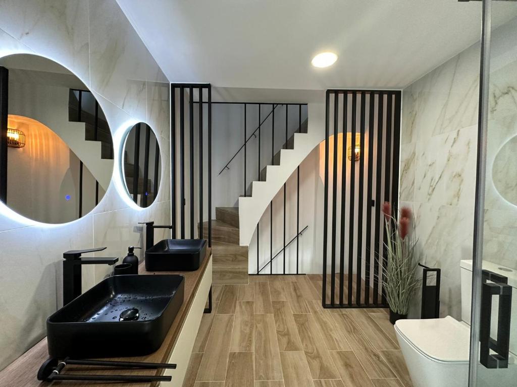 uma casa de banho com um lavatório preto e uma escada em La Mini Casa em Córdoba
