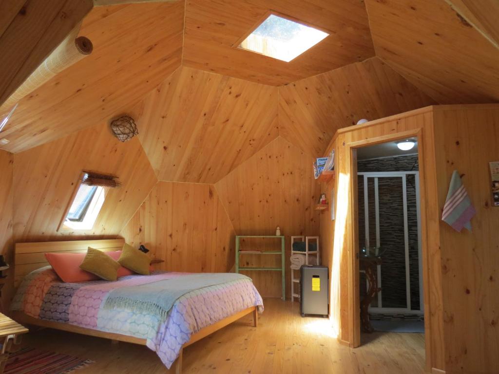 ein Schlafzimmer mit einem Bett in einer Holzhütte in der Unterkunft Lemunantu Domo Solar in La Ensenada
