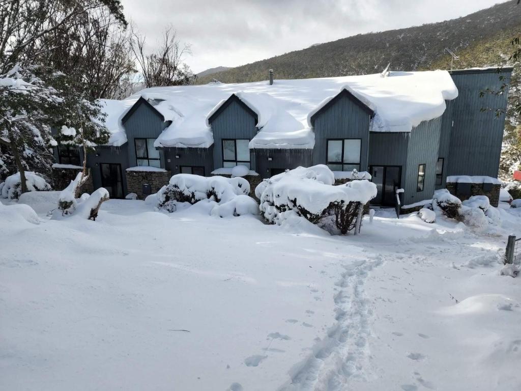 a house covered in snow with footprints in front of it at Snowcreek 2 Alpine Chalet, Private Garage in Thredbo
