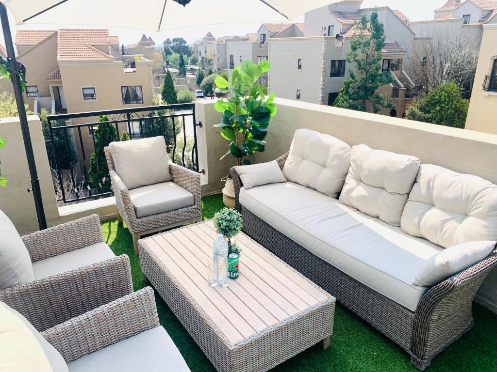 a couch and two chairs and a table on a balcony at Homey 2-bedroom apartment & loft space in Sandton
